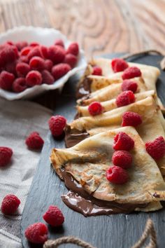 chocolate and raspberry crepes on a cutting board with fresh raspberries