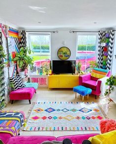 a living room filled with colorful furniture and lots of plants on the windows sill