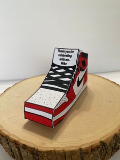 a paper shoe box sitting on top of a tree stump that says thank you for celebrating with nike