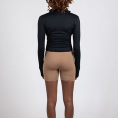 the back view of a woman in high waist shorts and black top, with her hands on her hips