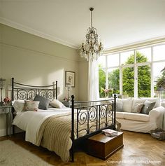 a bed room with a neatly made bed next to a couch and a large window