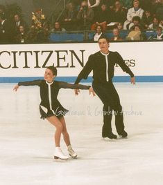 two people skating on an ice rink in front of a crowd