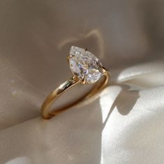 a yellow gold engagement ring with a pear shaped diamond on it's center piece