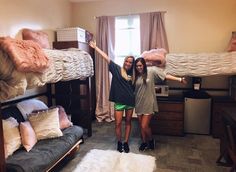 two girls standing in front of bunk beds with their arms up and one girl is holding her hand up