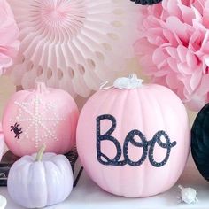 decorative pumpkins with the word boo painted on them and paper flowers in the background