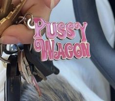 a close up of a person holding a keychain that says pussyy wagon