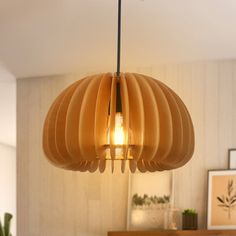 a wooden light fixture hanging from the ceiling in a room with white walls and wood furniture