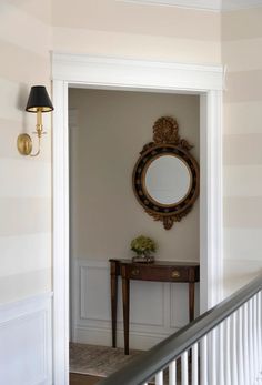 an entry way with a mirror, table and lamp