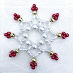 a snowflake made out of red and white ornaments on a white table cloth