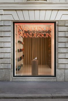 a store front window with a shoe display in the window and an orange neon sign above it