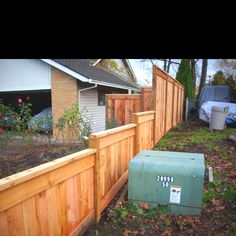 a wooden fence next to a house with a mailbox on the side of it