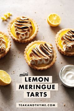 lemon meringue tarts with whipped cream and sliced lemons on the side