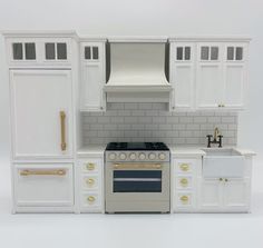 a model kitchen with white cabinets and gold trim on the stove, sink, and oven