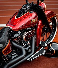 a red and black motorcycle parked on top of a tennis court covered in brown dirt