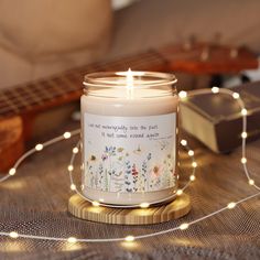 a lit candle sitting on top of a wooden table next to a string of lights