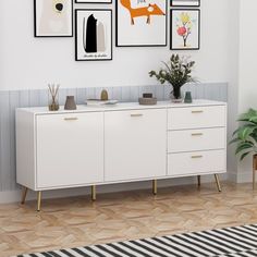 a white dresser with pictures on the wall and plants in vases next to it