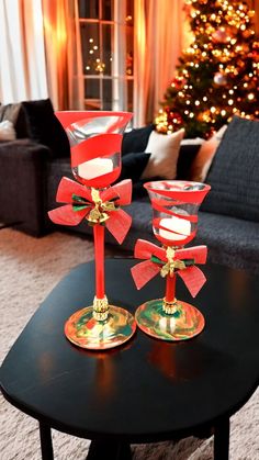 two red candlesticks sitting on top of a table in front of a christmas tree