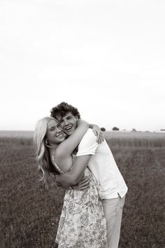 a man and woman hugging in an open field