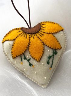 a heart shaped ornament with yellow flowers on it