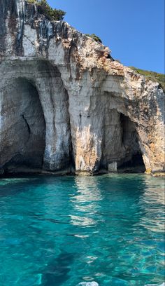 the water is crystal blue and there are some cliffs in the background that look like they have been built into the sea