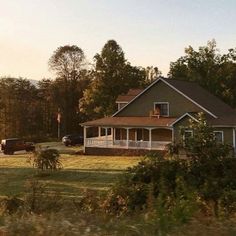 a large house sitting on top of a lush green field next to a wooded area