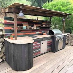 an outdoor kitchen made out of pallets and wooden planks, on a deck