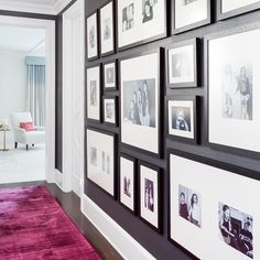 a wall with many pictures on it and a pink rug in front of the room