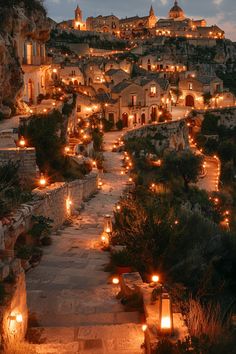 an old town with candles lit up on the steps leading to it at night time