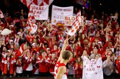 a man in red and white uniform standing on a basketball court with his hand up