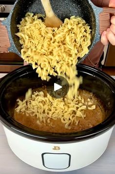 someone is pouring noodles into a slow cooker