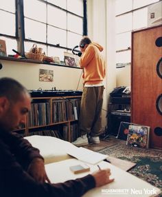 a man in an orange sweater writing on a piece of paper next to a record player