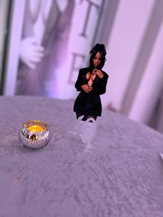 a small figurine sitting on top of a table next to a silver ball