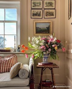 a living room with pictures on the wall and flowers in a vase next to a couch