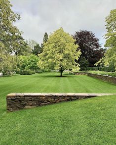 a stone wall in the middle of a grassy field