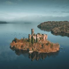 an island in the middle of water with birds flying around it