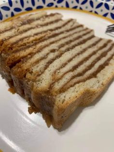 a grilled sandwich sitting on top of a white and yellow plate with a fork