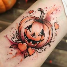 a tattoo with a pumpkin on it and hearts around the bottom half of its arm