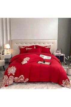 a bed with red comforters and pillows in a room next to a window,