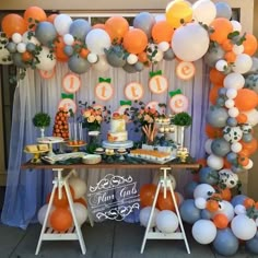 an orange and white dessert table with balloons