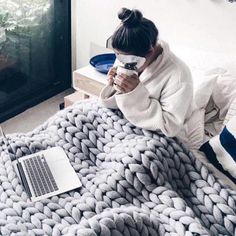 a woman sitting on top of a bed with a laptop computer next to her face