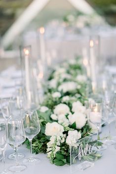 the table is set with white flowers and greenery for an elegant wedding reception or special event