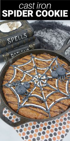 a cast iron spider cookie sitting on top of a table next to some halloween books