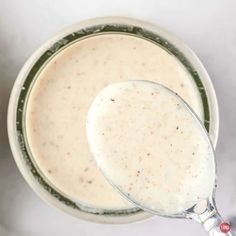 a spoon in a bowl filled with cream sauce on top of a white tablecloth