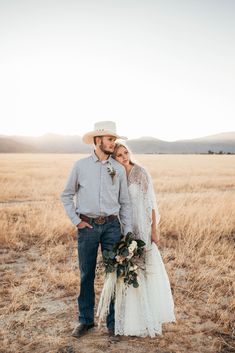 a bride and groom standing together in the middle of an open field with tall grass