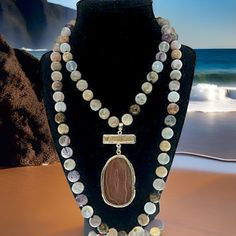 The Beachcomber necklace is a perfect way to bring the ocean's magic into your everyday look. Adorned with beads, stones, and crystals in calming colors, it evokes the peaceful beauty of the beach at dawn. The 33-inch length and versatile pendant make it the perfect accessory for any occasion. Imagine the joy of a day at the beach, everywhere you go! Bohemian Ocean Jasper Necklace For Gifts, Bohemian Ocean Jasper Necklace As Gift, Bohemian Ocean Jasper Necklaces For Gifts, Bohemian Ocean Jasper Necklaces As Gifts, Spiritual Beaded Agate Jewelry, Bohemian Ocean Jasper Gemstone Beads Jewelry, Adjustable Ocean Jasper Necklaces With Natural Stones, Bohemian Jewelry With Ocean Jasper Gemstone Beads, Handmade Agate Necklace For Beach