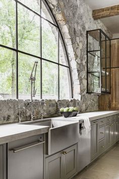 a kitchen with stone walls and large windows