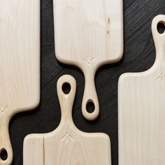 three wooden cutting boards sitting on top of a black table with holes in the middle