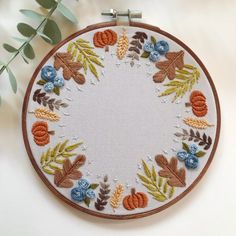 an embroidered hoop with leaves and berries on it