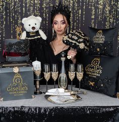 a woman holding a teddy bear in front of a table with wine glasses and gifts