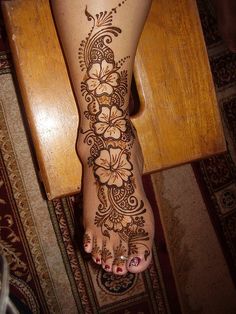 a woman's foot with henna tattoos on it, and flowers painted on the bottom